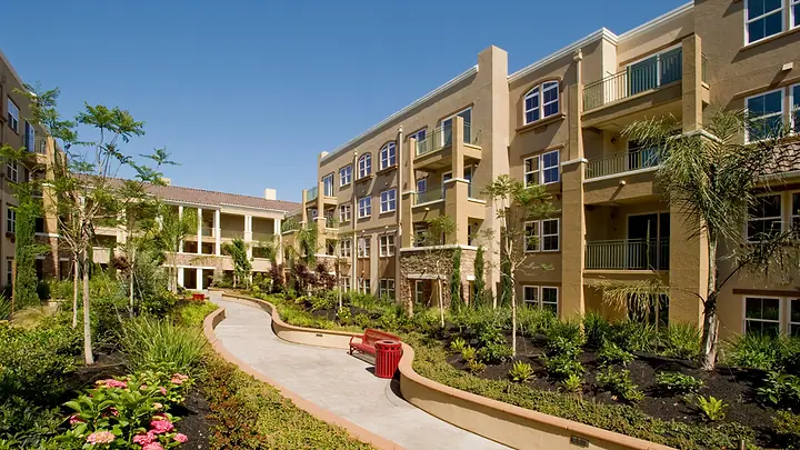 Condomínio residencial de prédios baixos com jardim e caminho entre os blocos