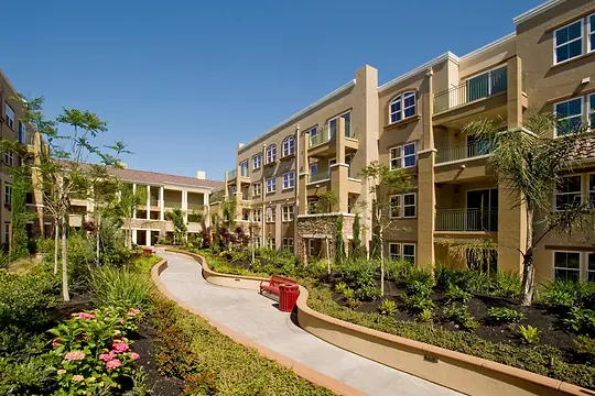 Condomínio residencial de prédios baixos com jardim e caminho entre os blocos