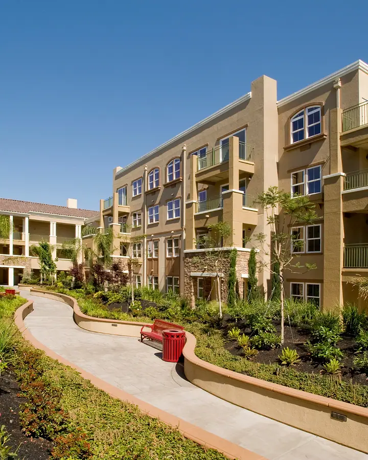 Condomínio residencial de prédios baixos com jardim e caminho entre os blocos