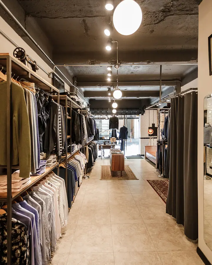 Corredor de uma loja de roupas masculinas com araras dos dois lados
